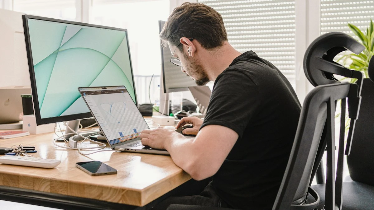 Web designer working at a laptop beside a large monitor